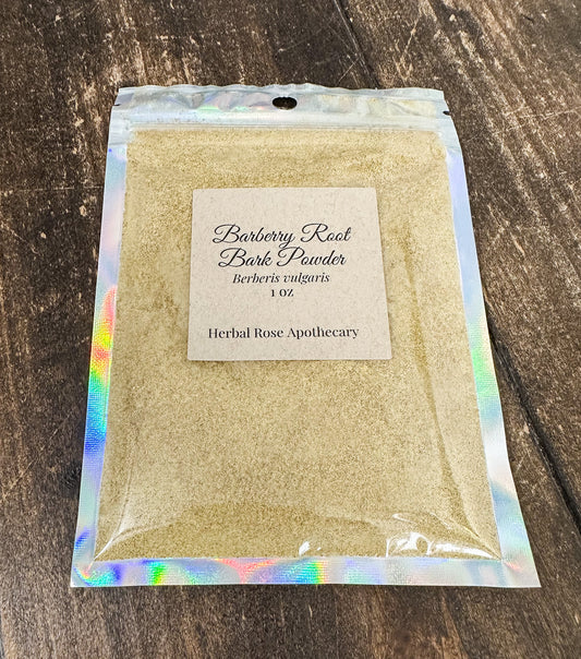 A 1 oz bag of Herbal Rose Apothecary Barberry Root Bark Powder, filled with light tan powder and sealed in a holographic silver pouch, displayed on a dark wood background.