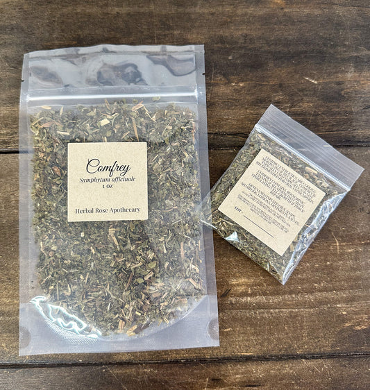 Two packages of Comfrey from Herbal Rose Apothecary on a wooden surface.