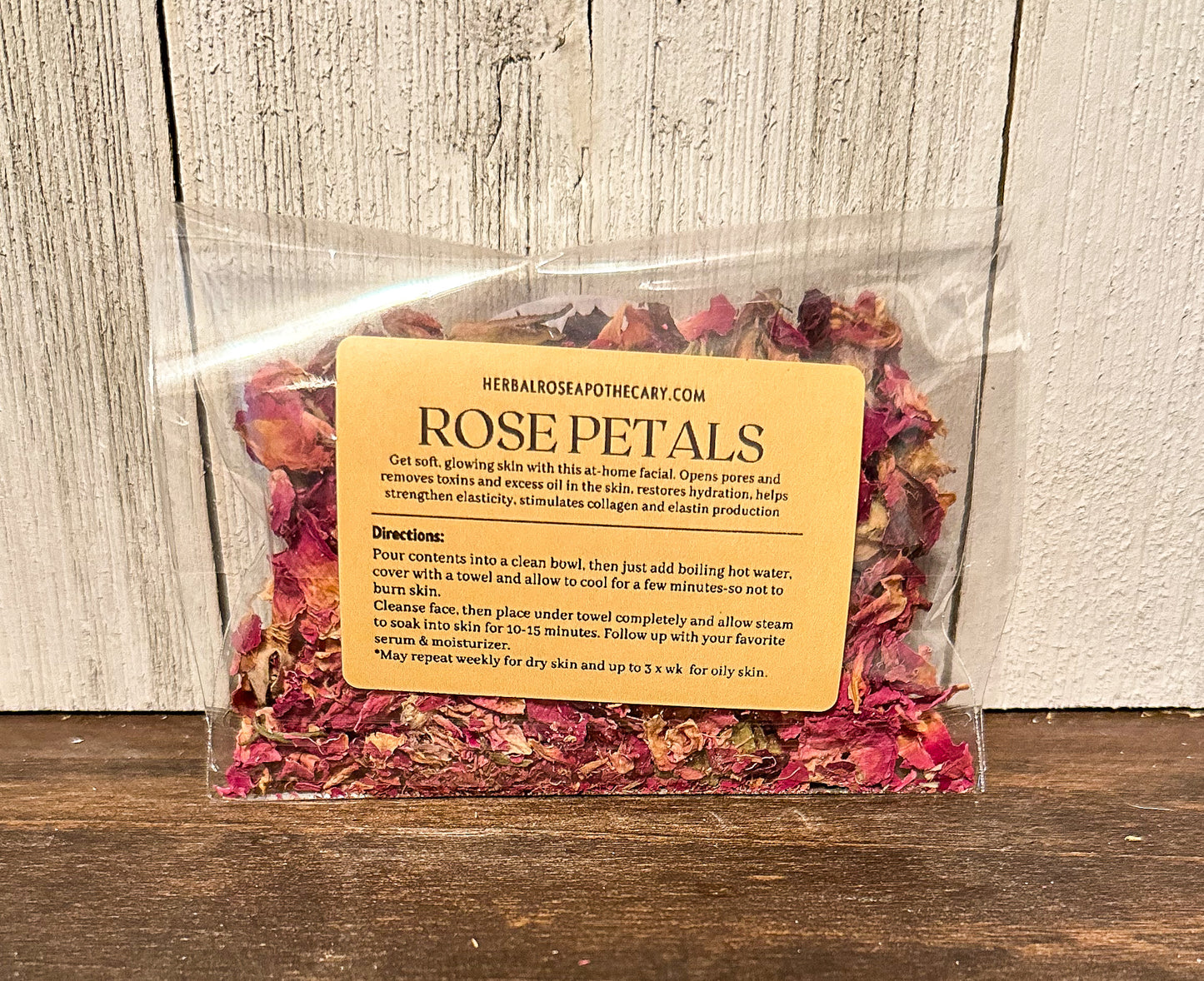 facial steamers rose with label showing directions and benefits, brown table with white wood background packaged in cellophane