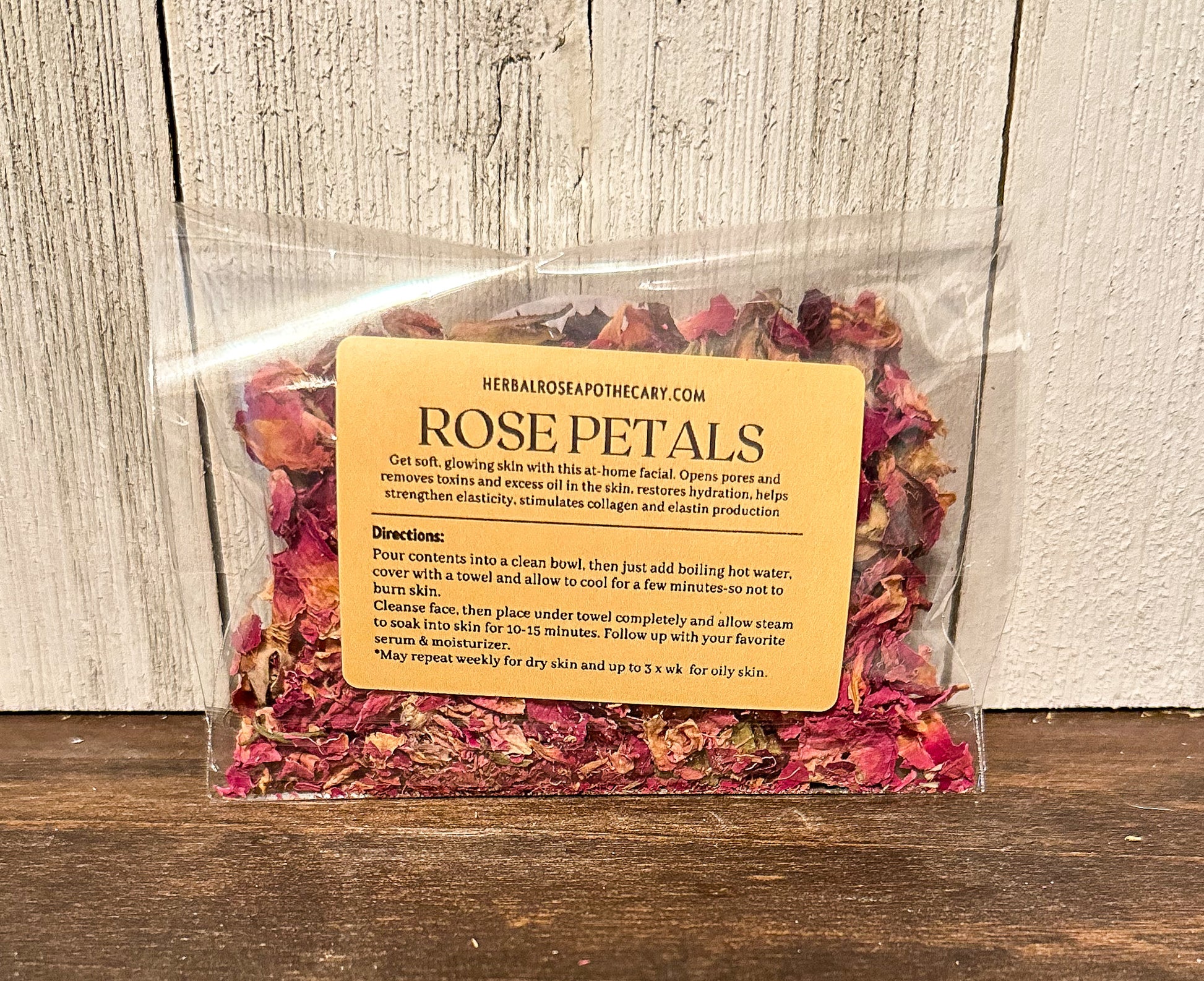 facial steamers rose with label showing directions and benefits, brown table with white wood background packaged in cellophane