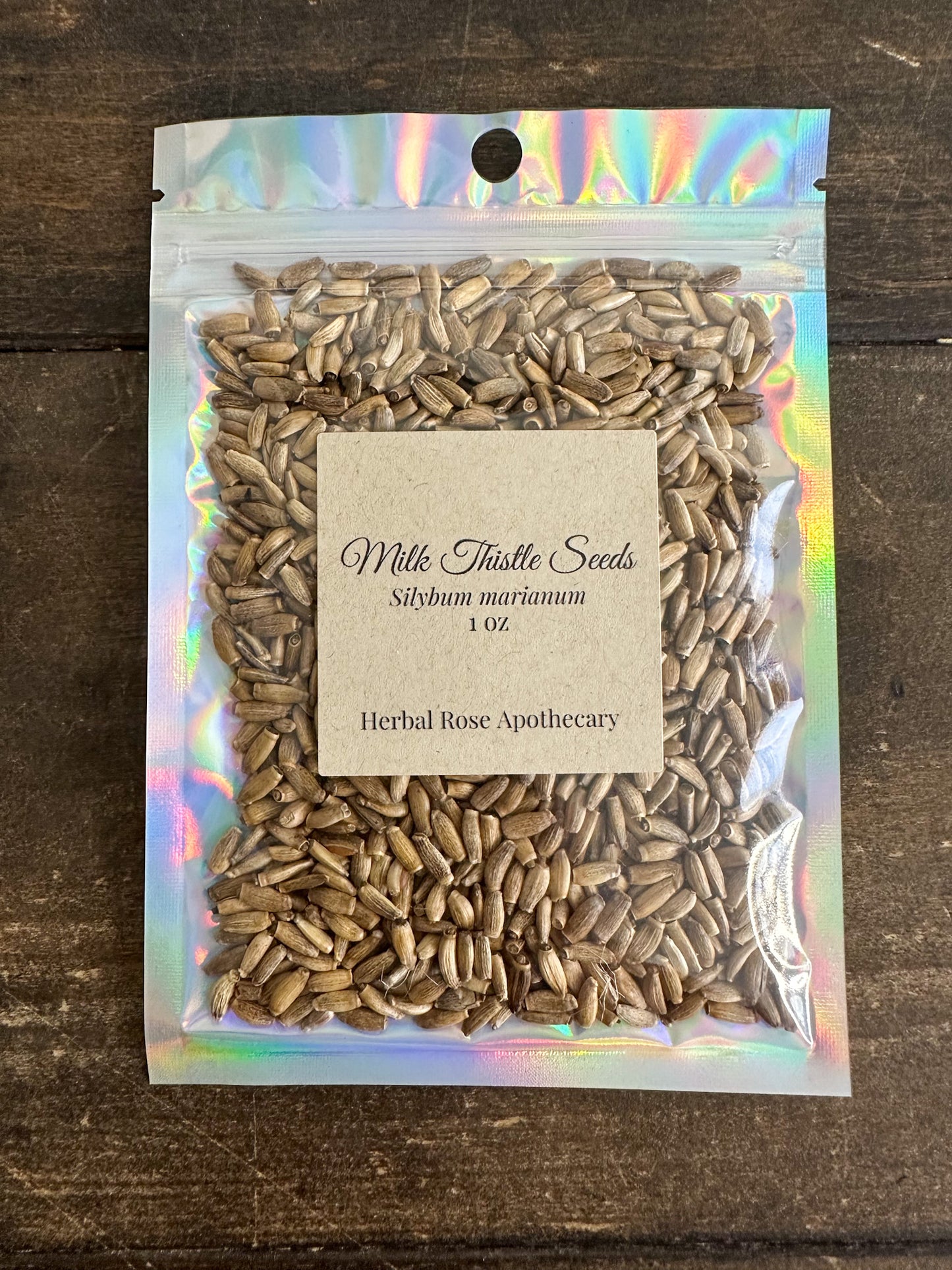 Packaged milk thistle seeds 1oz bag with a label on a wooden surface