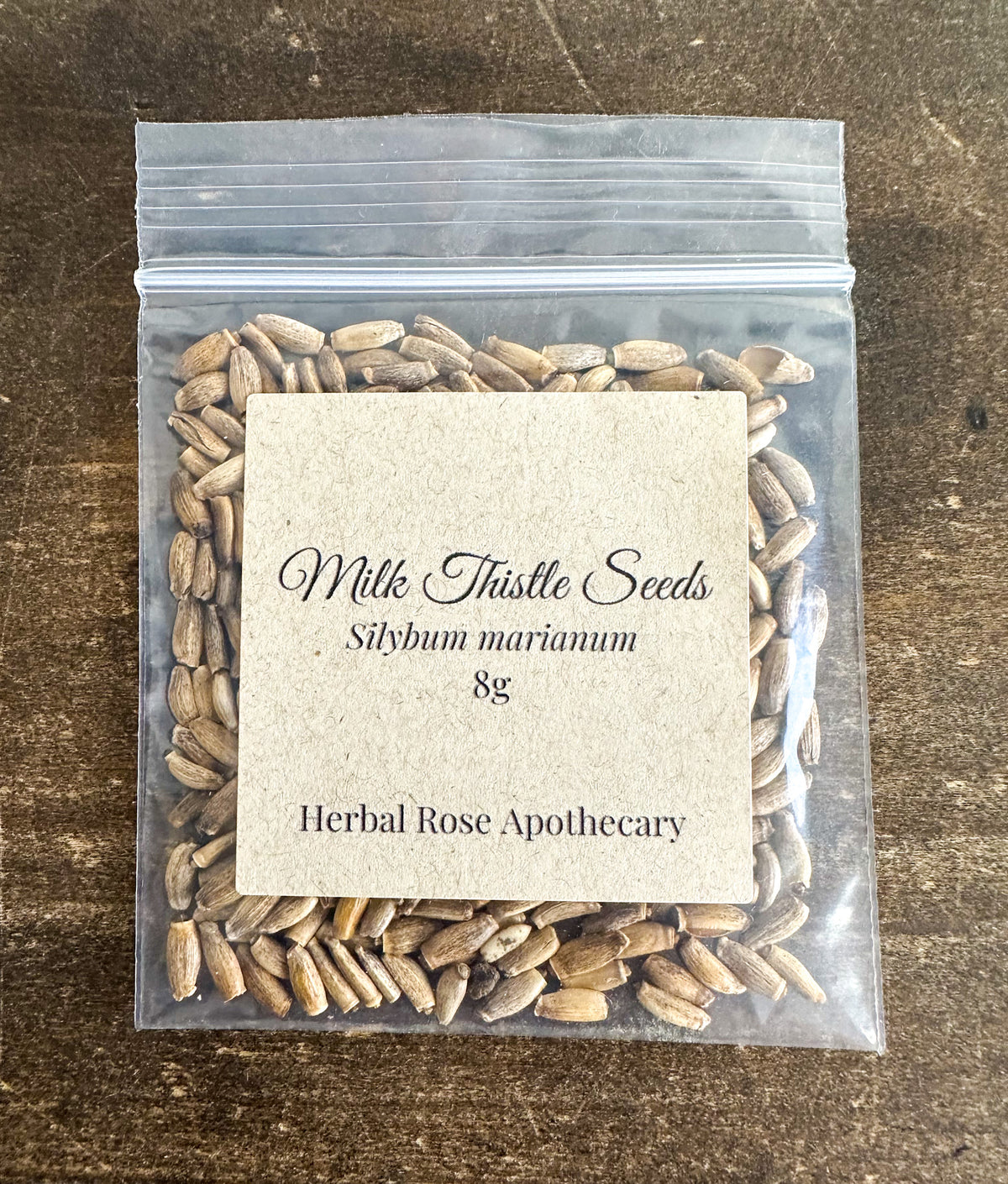 milk thistle seeds in 8g resealable bag on a wooden surface
