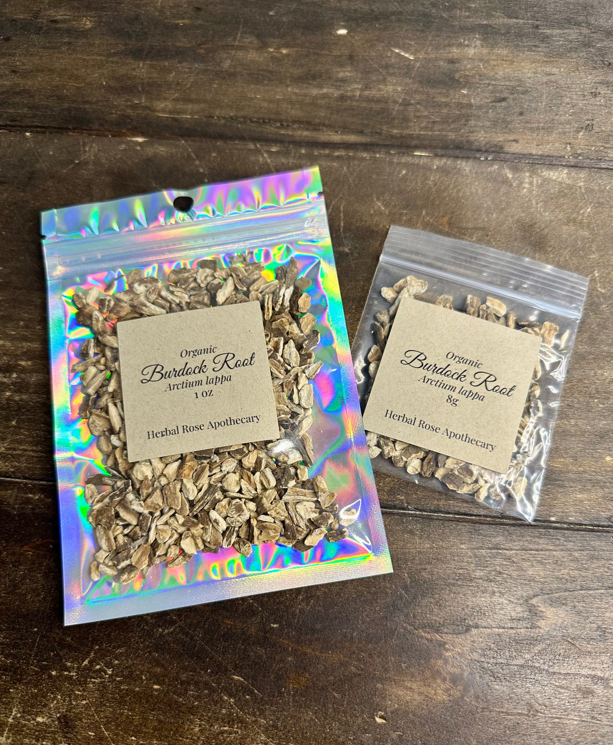 two packages of dried organic burdock root from herbal rose apothecary on a wooden surface