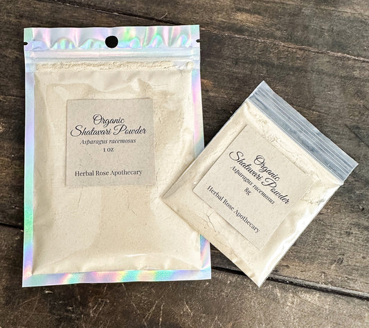 Two packages of Organic Shatavari Powder from Herbal Rose Apothecary on a wooden surface.