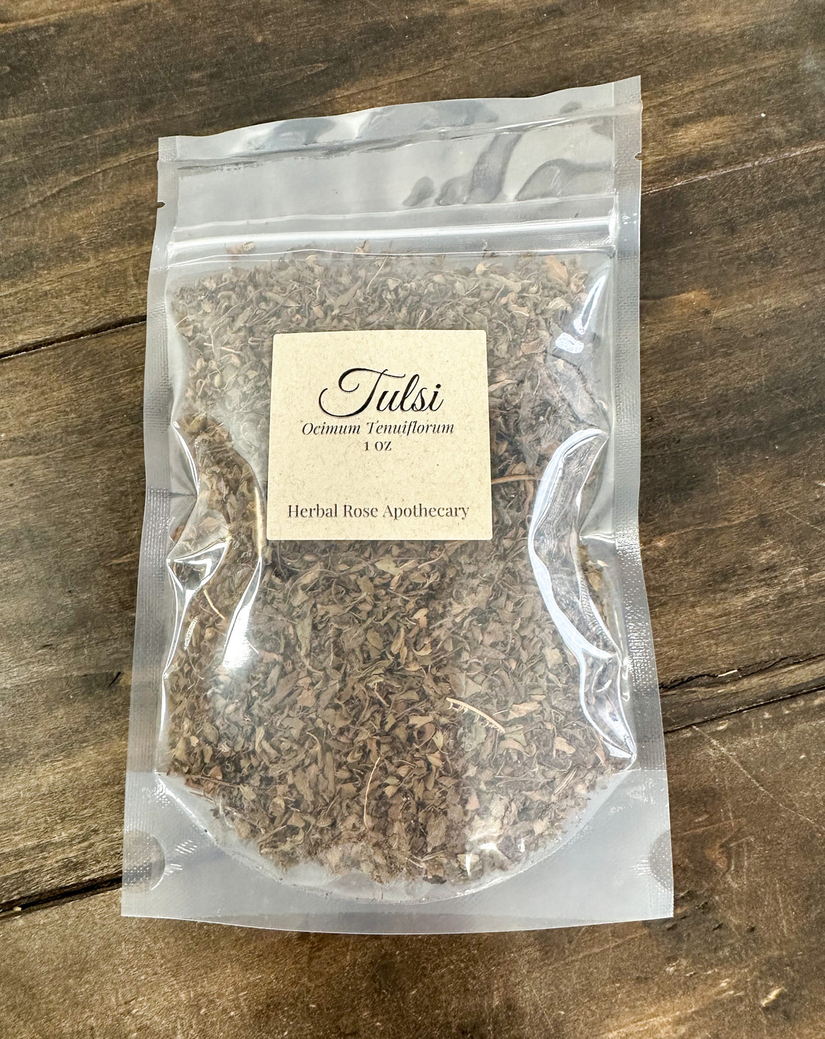 dried tulsi leaves in 1oz clear resealable bag on wooden surface