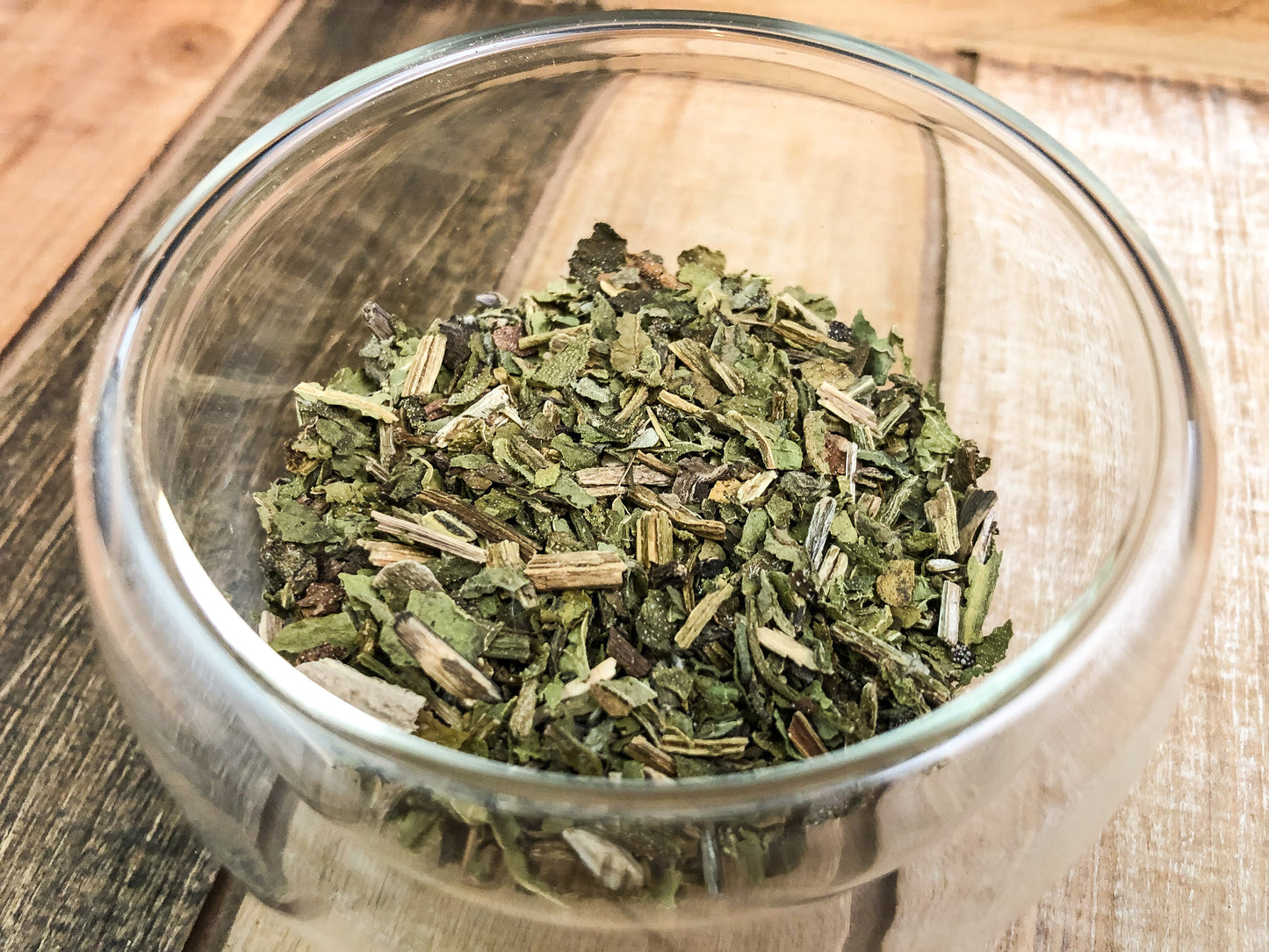 upclose image of dried comfrey in clear glass cup with wooden background
