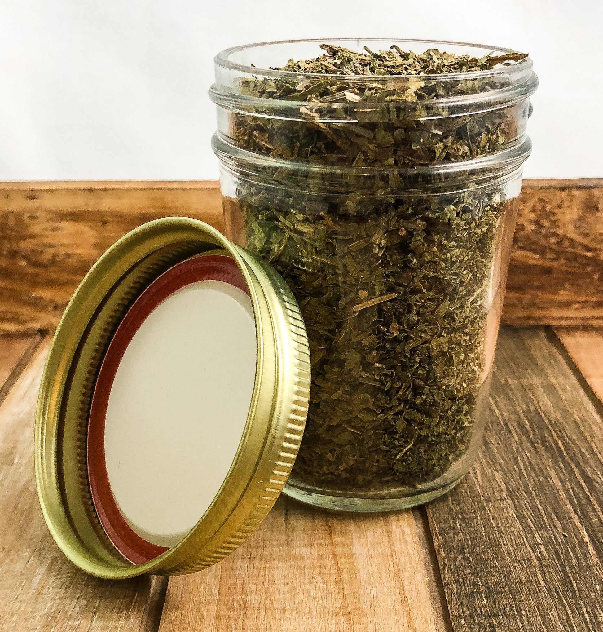 dried comfrey in a clear mason jar with a wooden background