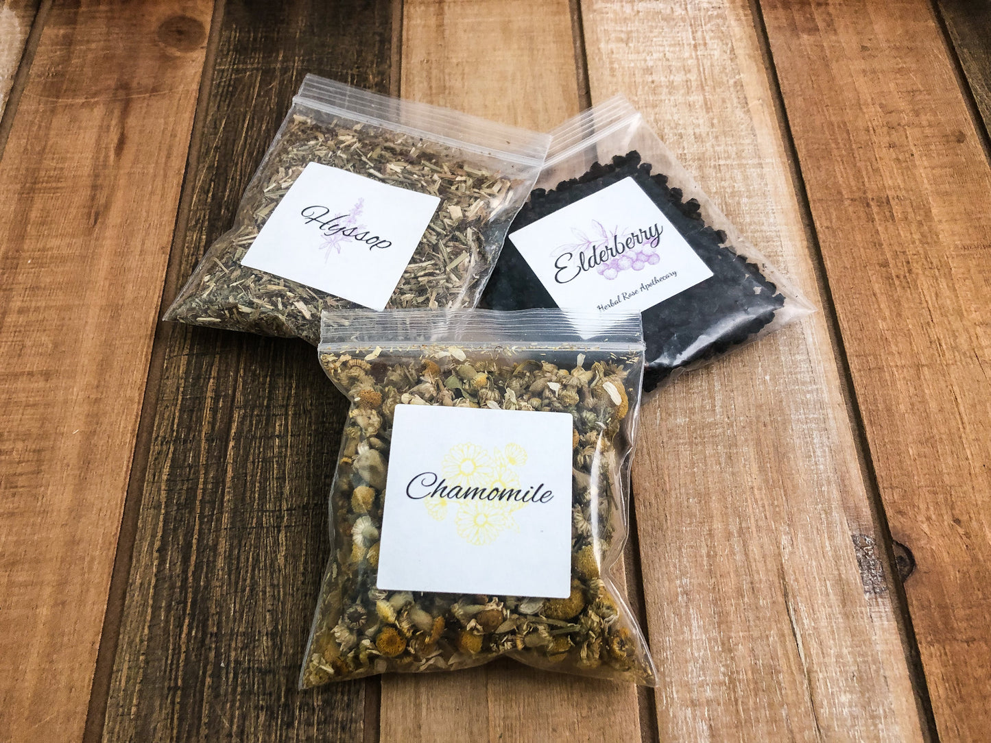 8g clear plastic bags of dried elderberry, chamomile, and hyssop on a wooden background