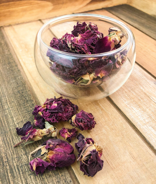 rose petals in a glass cup on a wooden tray