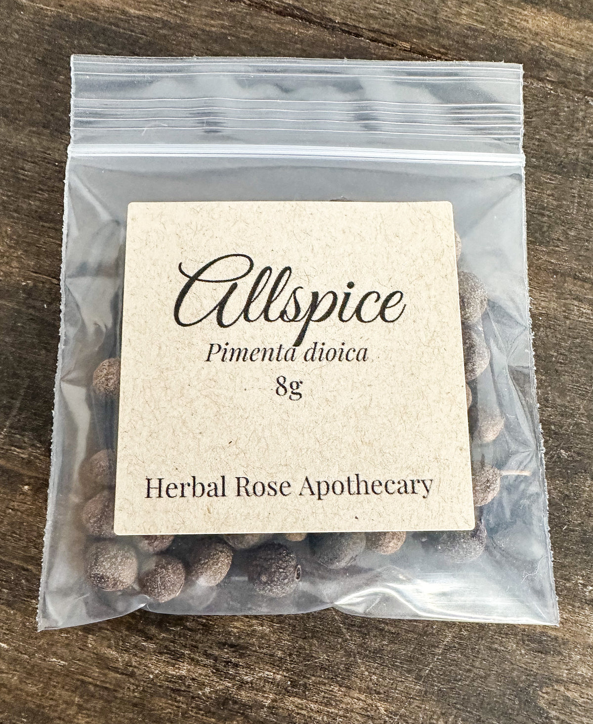 Packaged allspice with a 8g label on a wooden surface