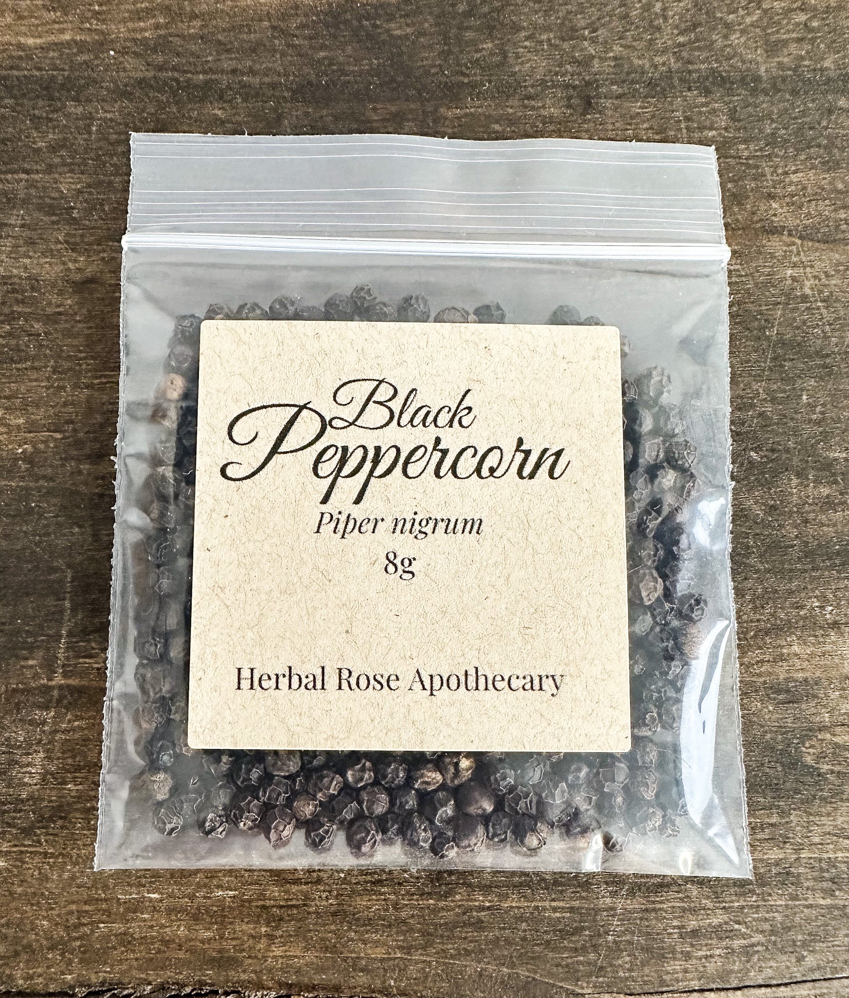 Packaged black peppercorns with a label on a wooden surface
