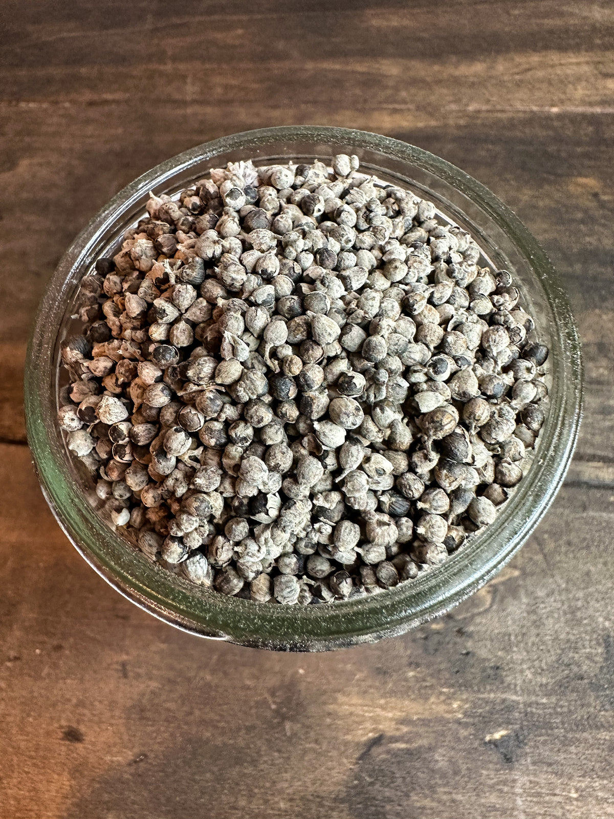 A top-down view of dried chasteberry,  set on a rustic dark wood background.