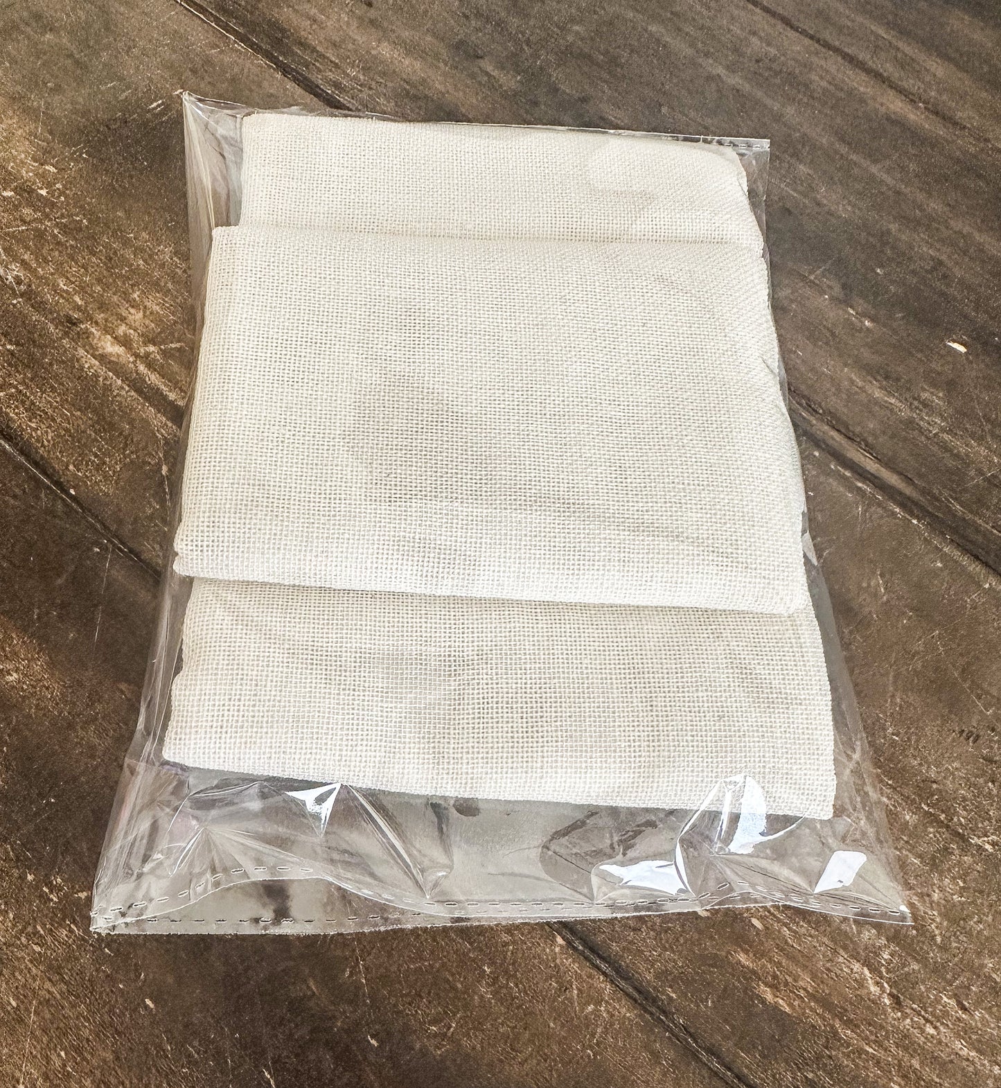 three cheesecloths in a clear plastic bag on a wooden surface