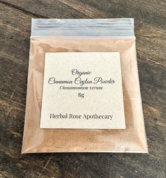 Packaged organic cinnamon powder from Herbal Rose Apothecary on a wooden surface