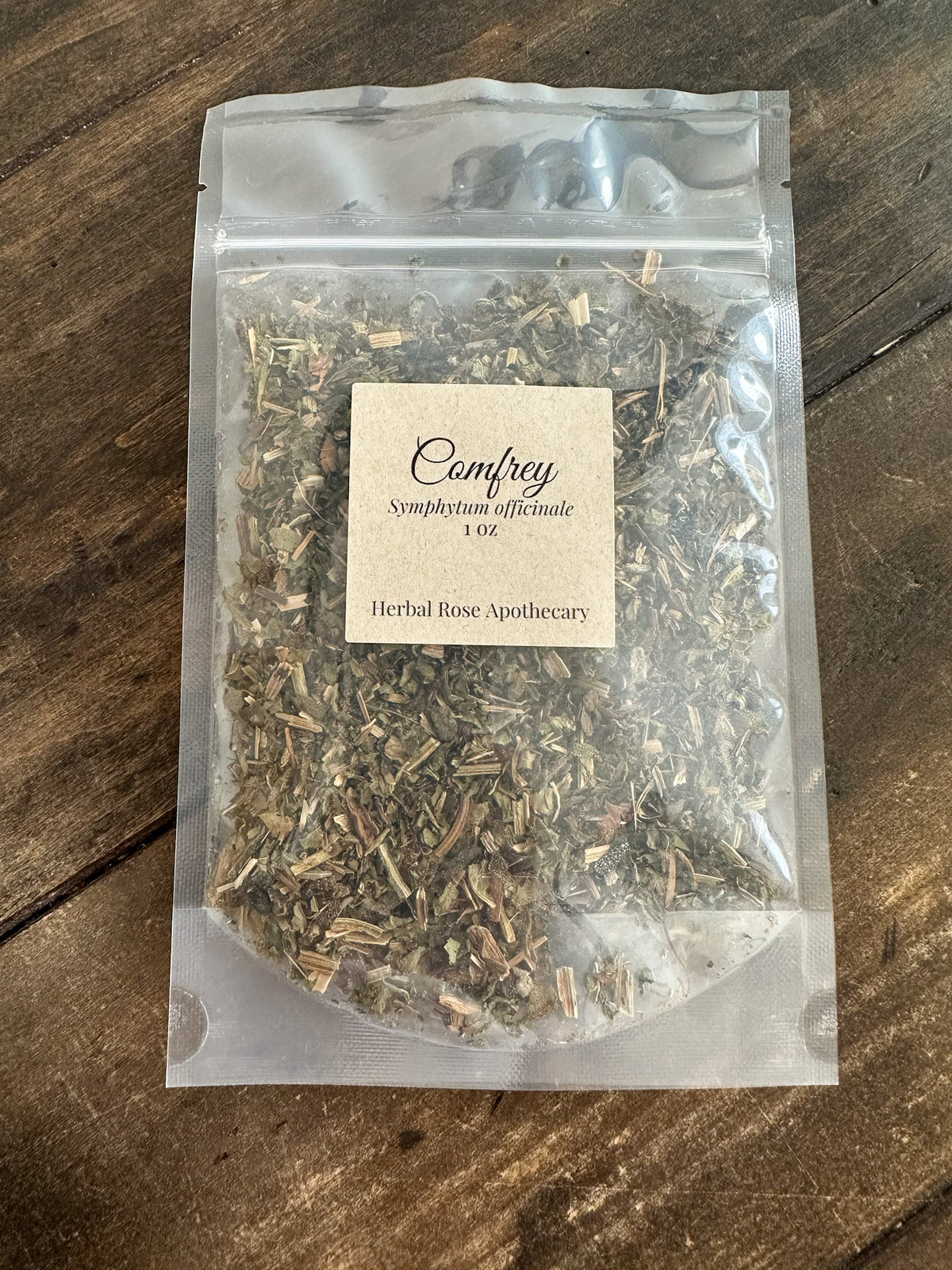 Clear package of Comfrey 1oz on a wooden surface