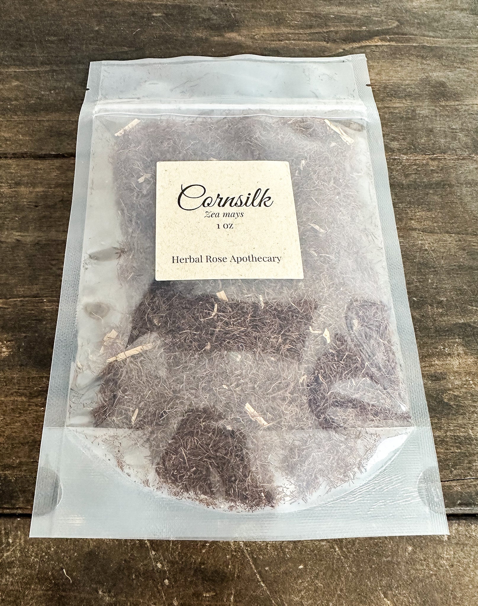 Clear package with herbs labeled 'Cornsilk' on a wooden surface