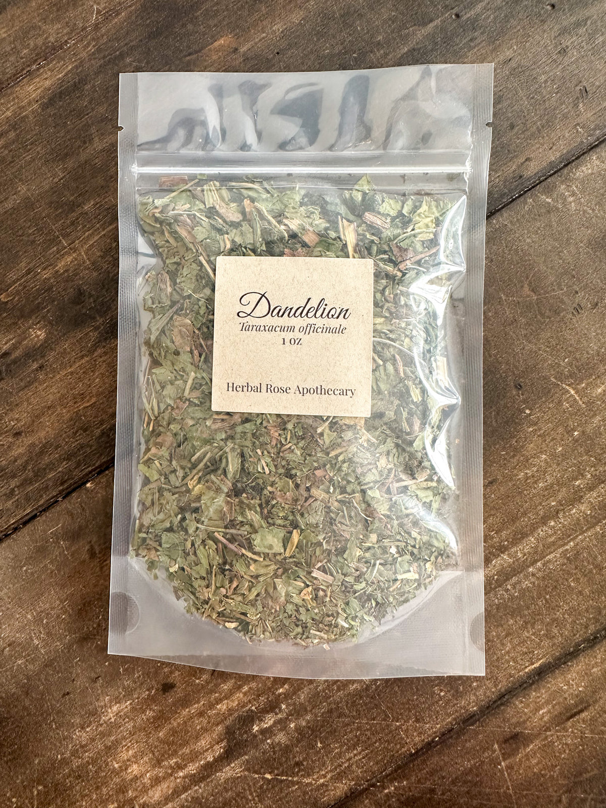 Packaged dandelion herb 1oz bag on a wooden surface with 'Dandelion' label.