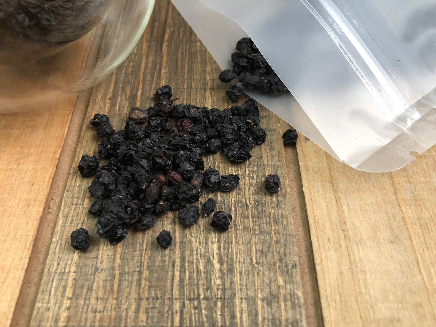 dried elderberries spilling out an oqaue opened bag on wooden surface