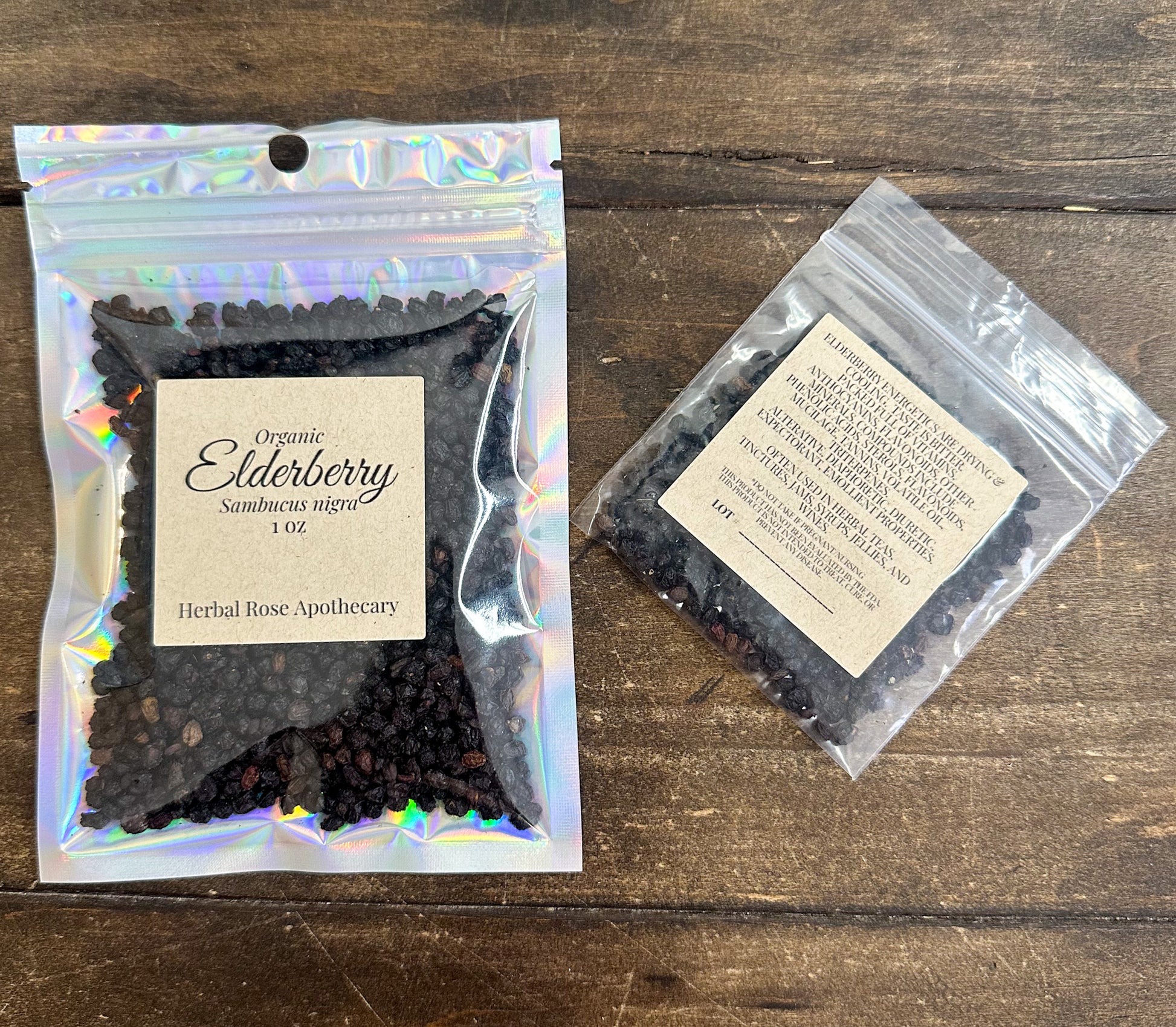 two packages of dried organic elder berry in resealable bags from herbal rose apothecary on a wooden surface