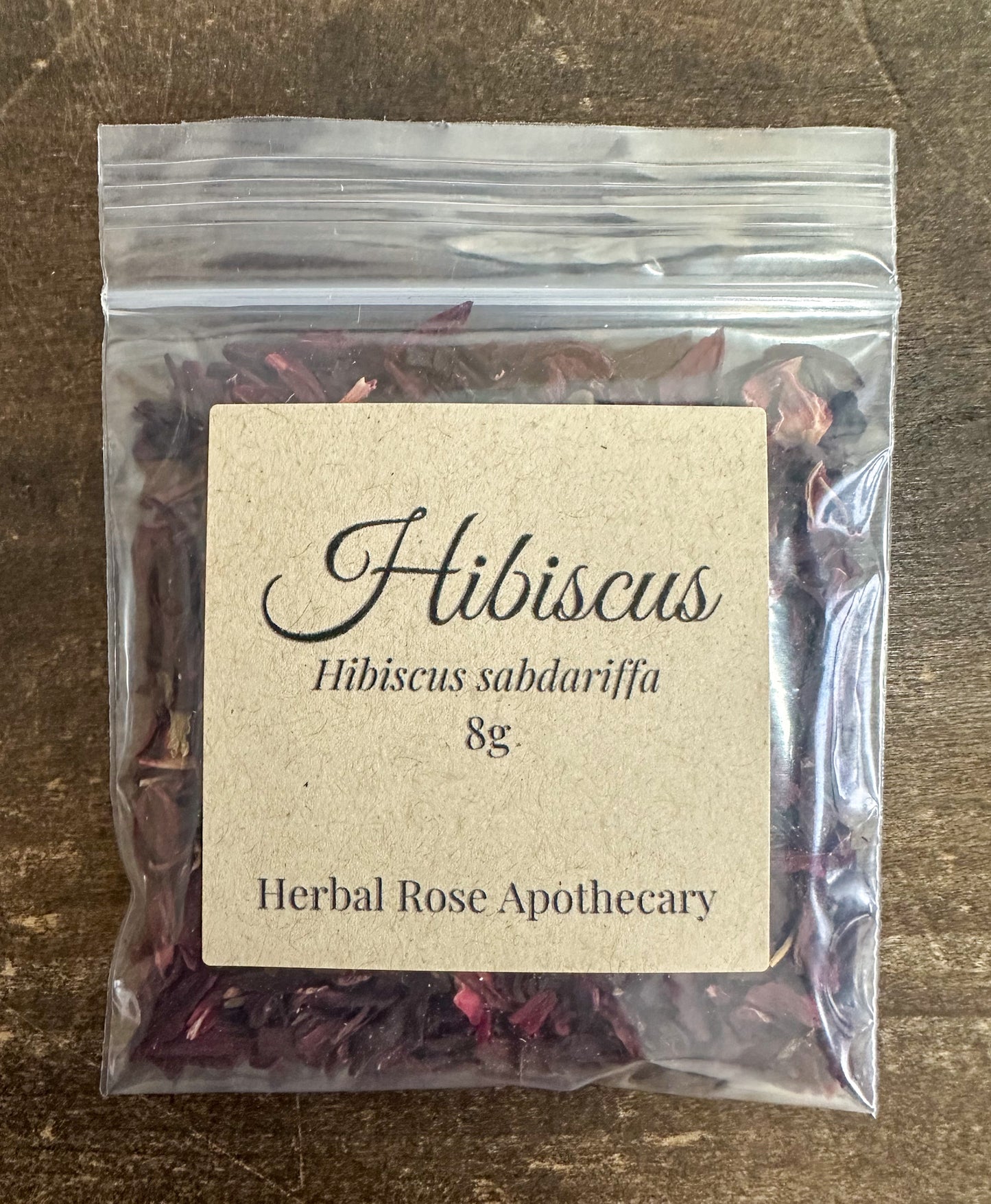 dried hibiscus 8g in clear resealable bag on wooden surface