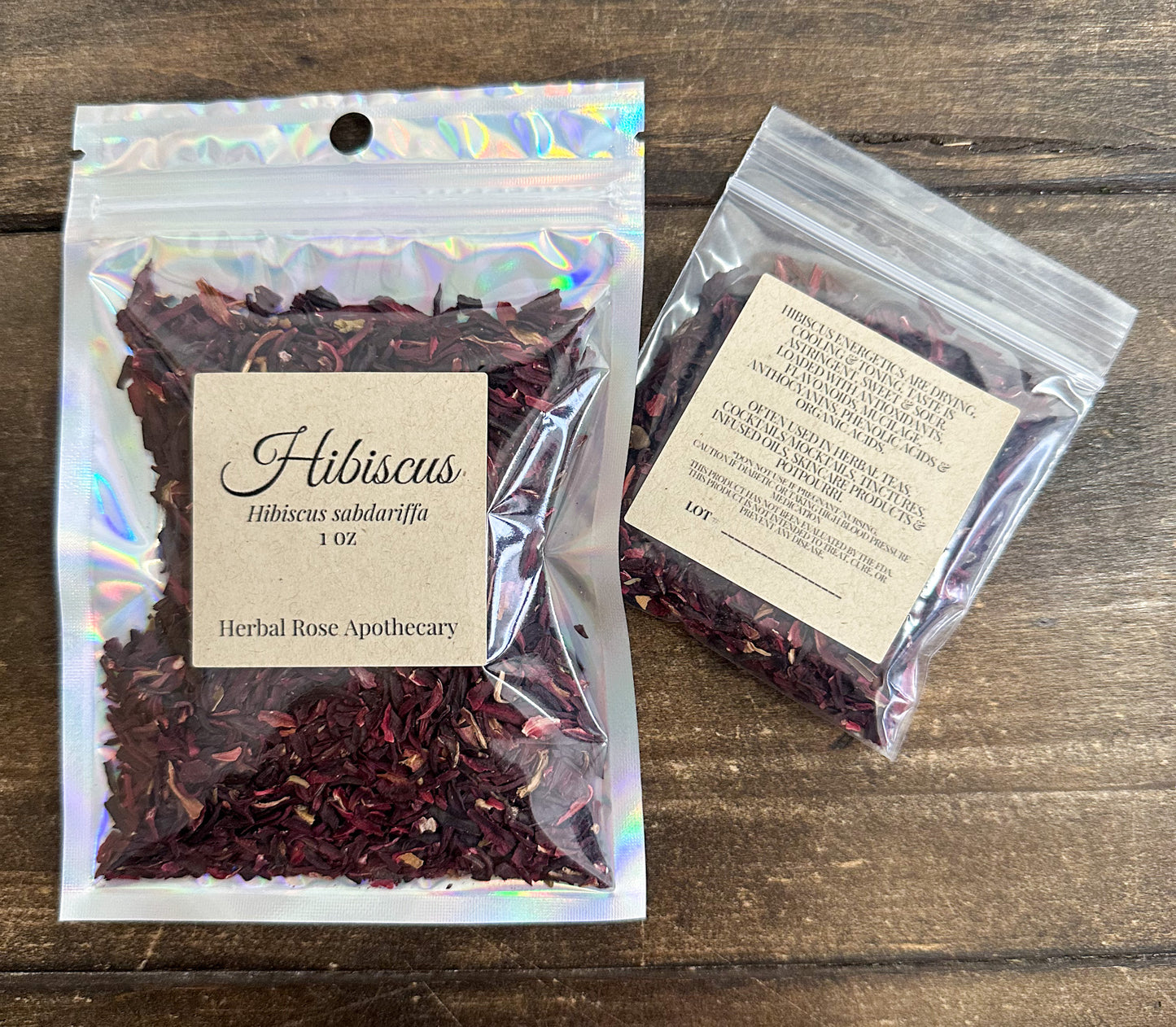 two packages of dried hibiscus leaves in clear resealable bags from herbal rose apothecary on a wooden surface