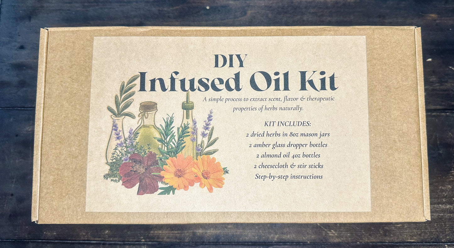 DIY Infused Oil Kit in a square kraft paper box with a cream label featuring botanical illustrations and product text, photographed from above on a dark wooden surface.