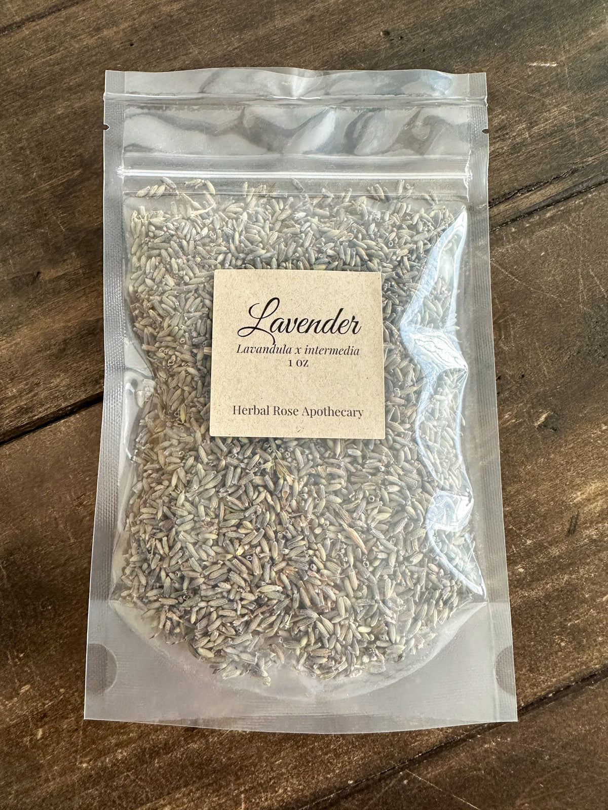 dried lavender buds packaged up in a clear 1oz bag on a wooden surface