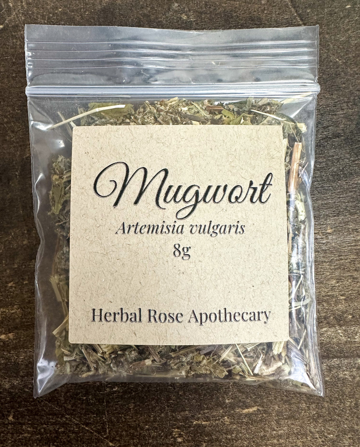 dried mugwort packaged into a 8g clear resealable bag on a wooden surface