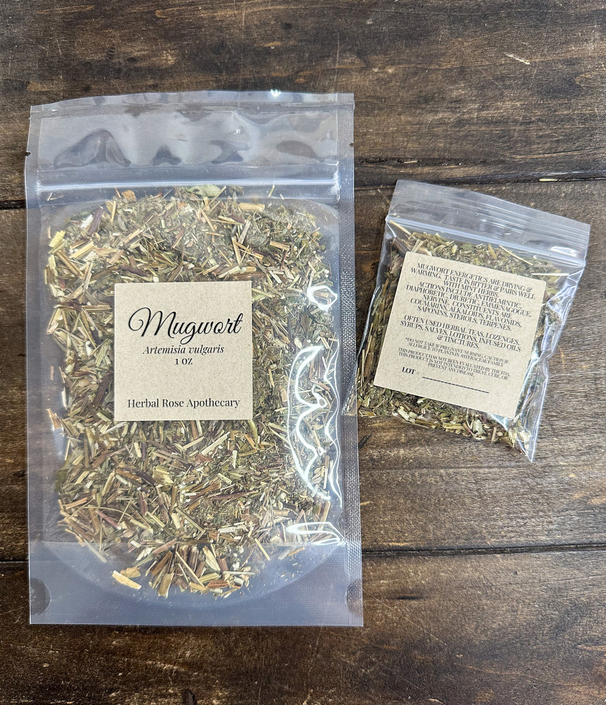 two packages of dried mugwort in clear resealable packages on a wooden surface from herbal rose apothecary