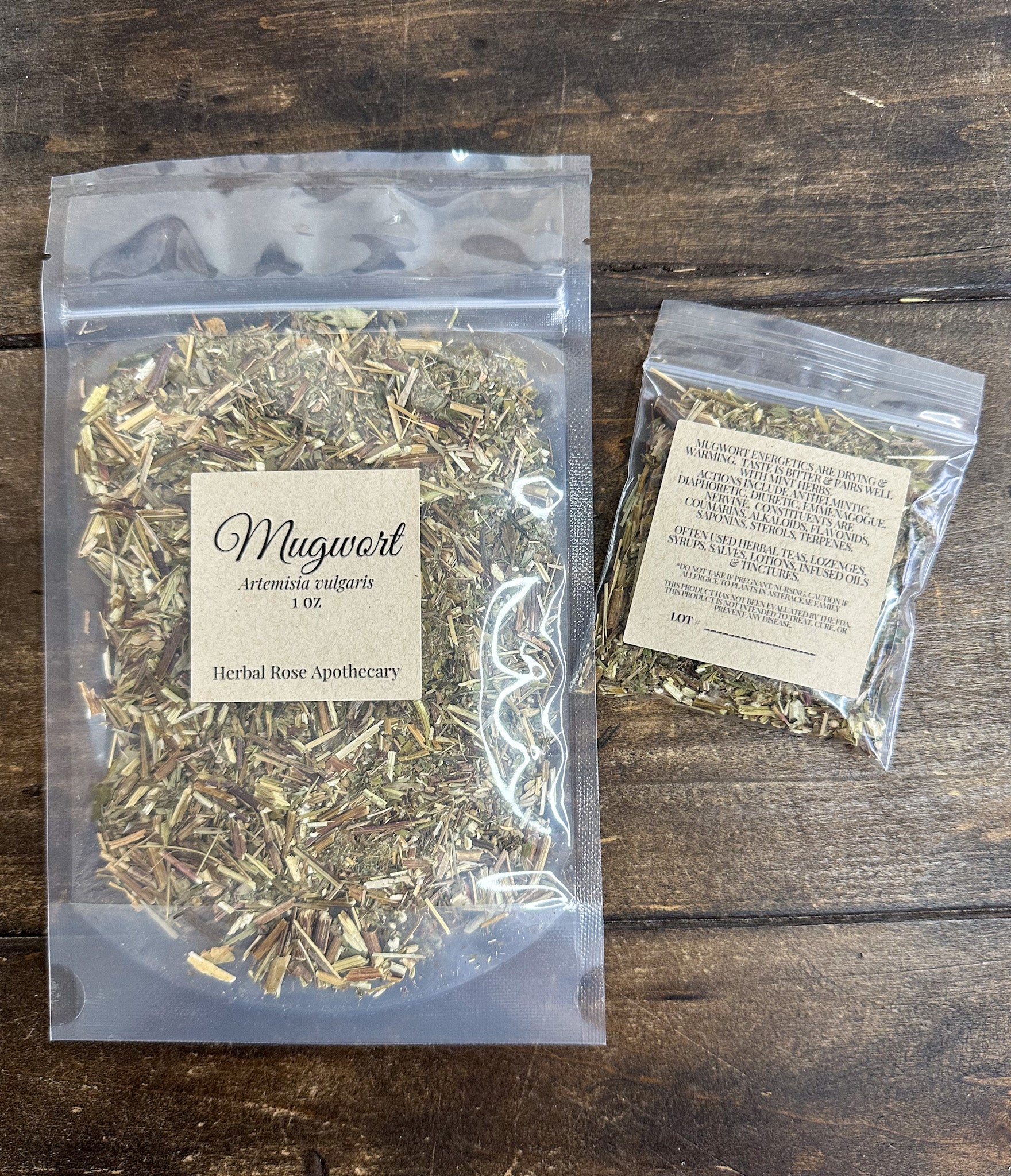 two packages of dried mugwort in clear resealable packages on a wooden surface from herbal rose apothecary