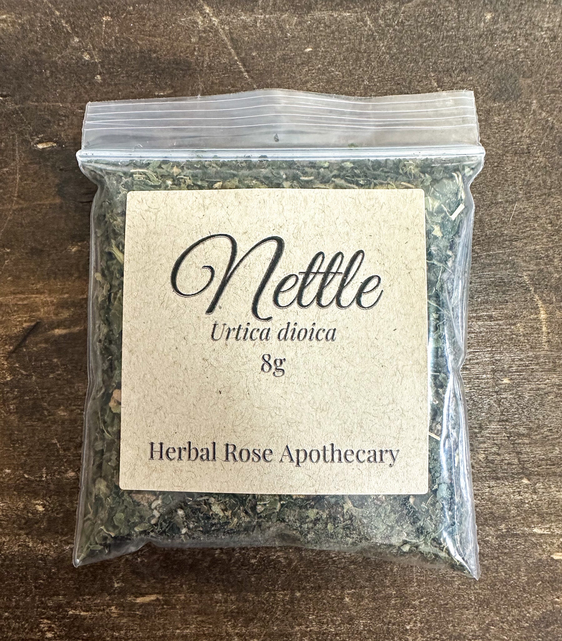 dried nettle leaves in a 8g resealable clear bag on a wooden surface
