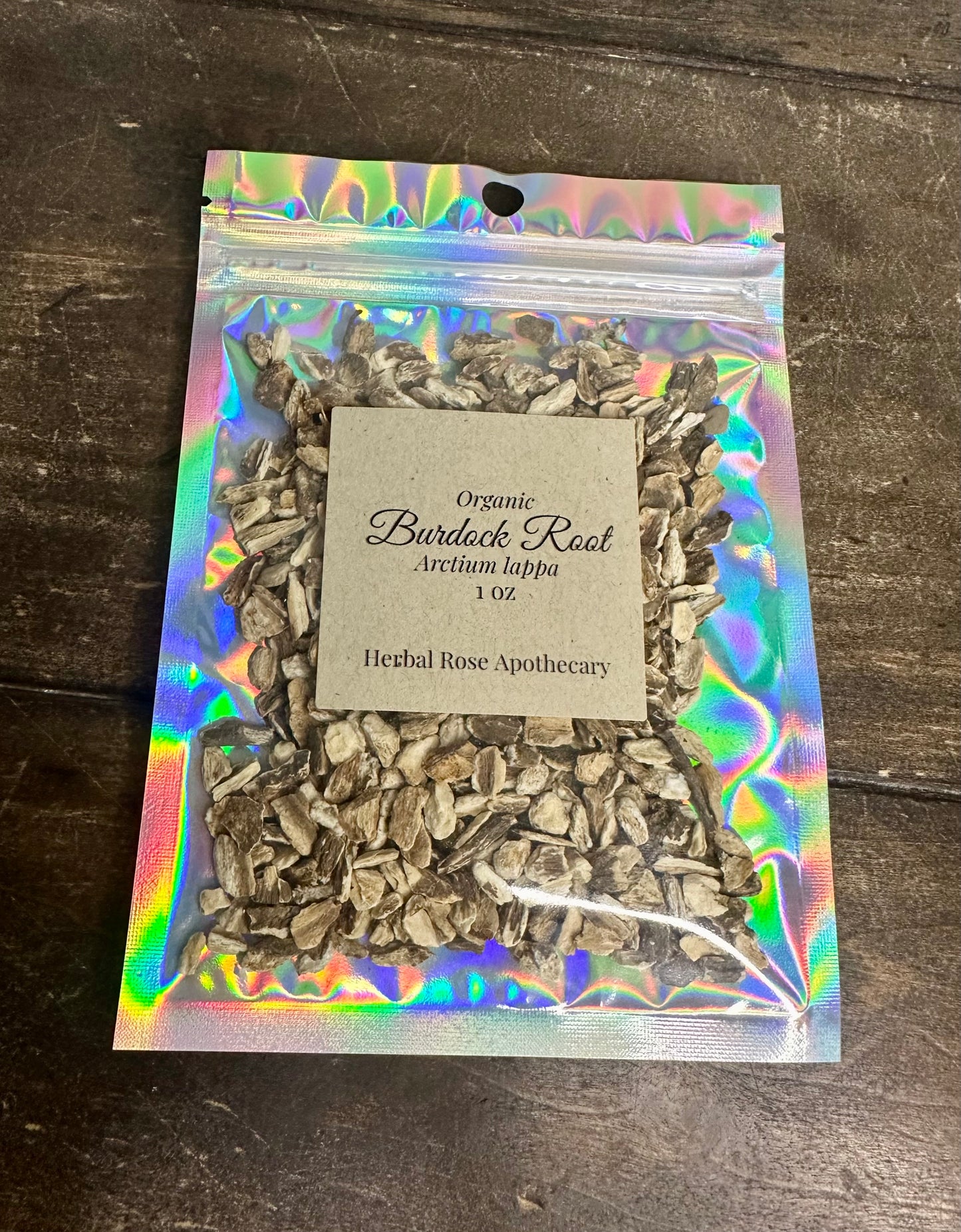 dried organic burdock root in holographic bag on wooden surface