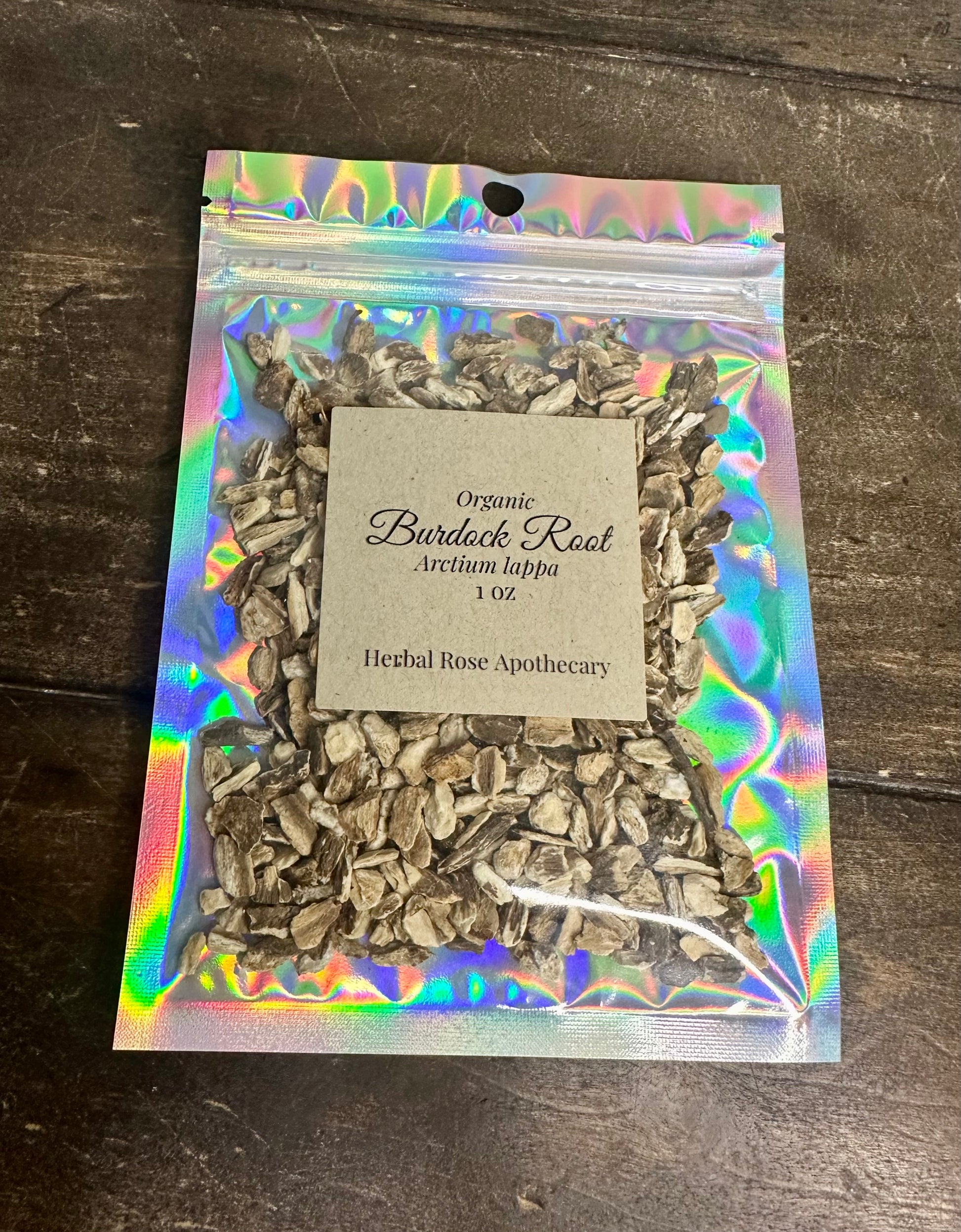 dried organic burdock root in holographic bag on wooden surface