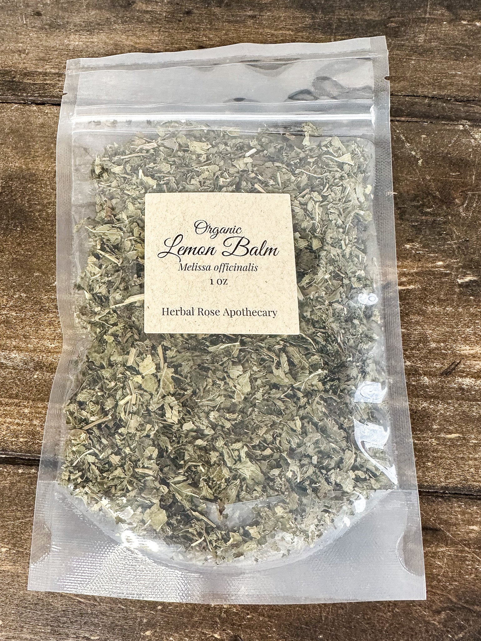 dried organic lemon balm leaves in a resealable clear bag on a wooden surface