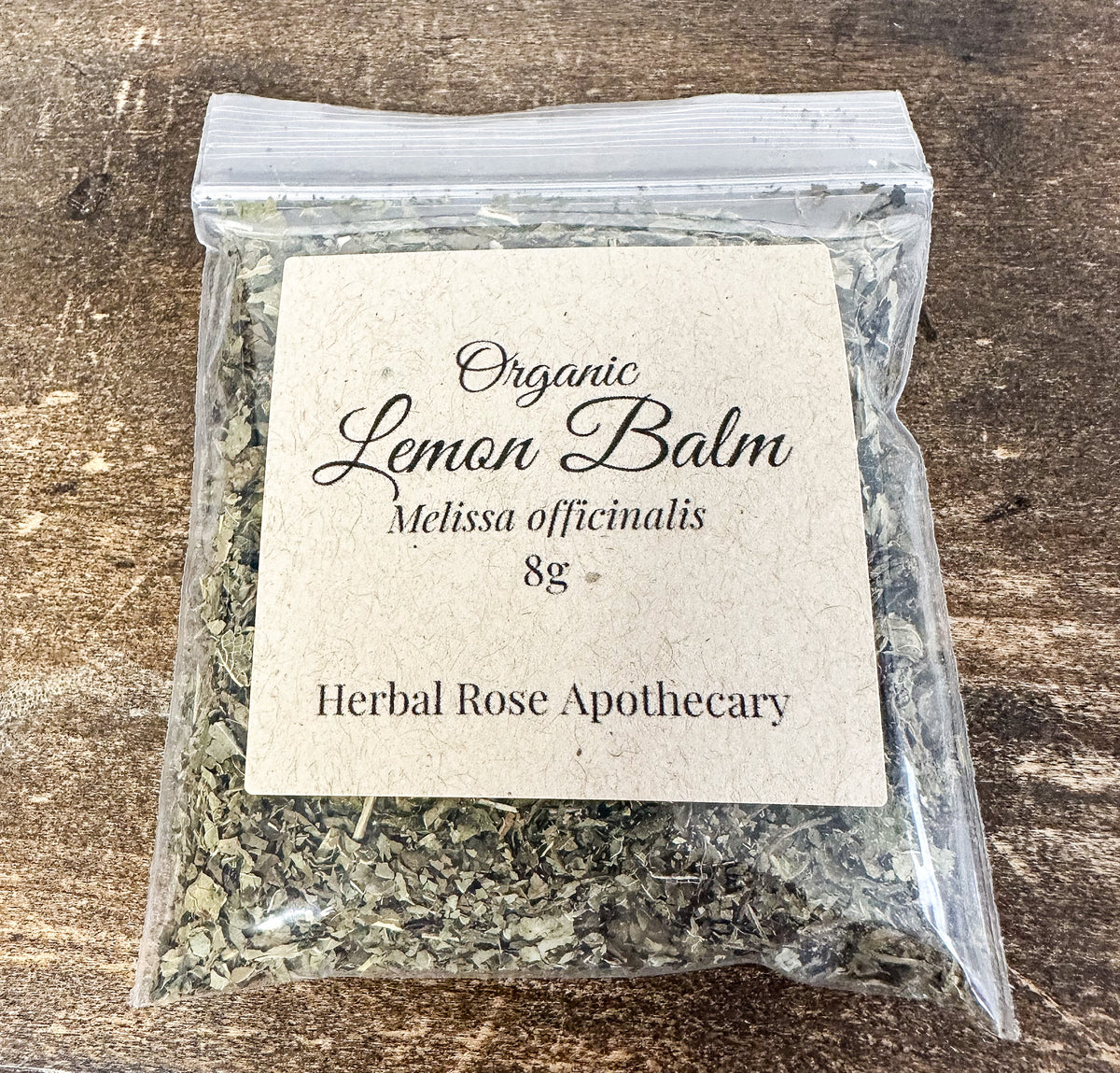 dried organic lemon balm in 8g clear resealable bag on a wooden surface
