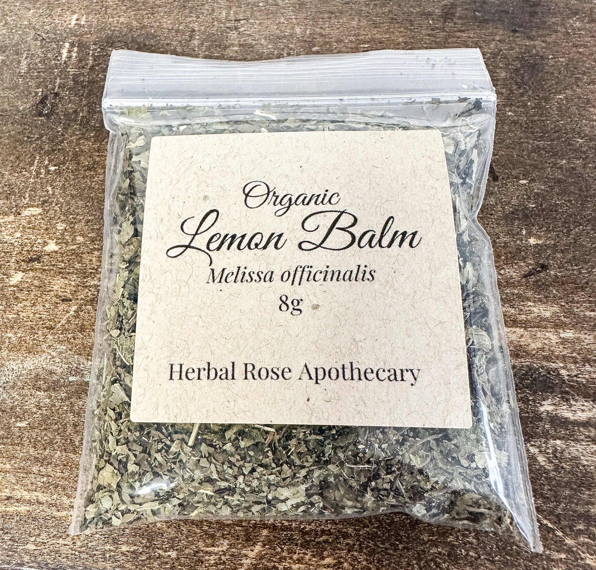 dried organic lemon balm in 8g clear resealable bag on a wooden surface