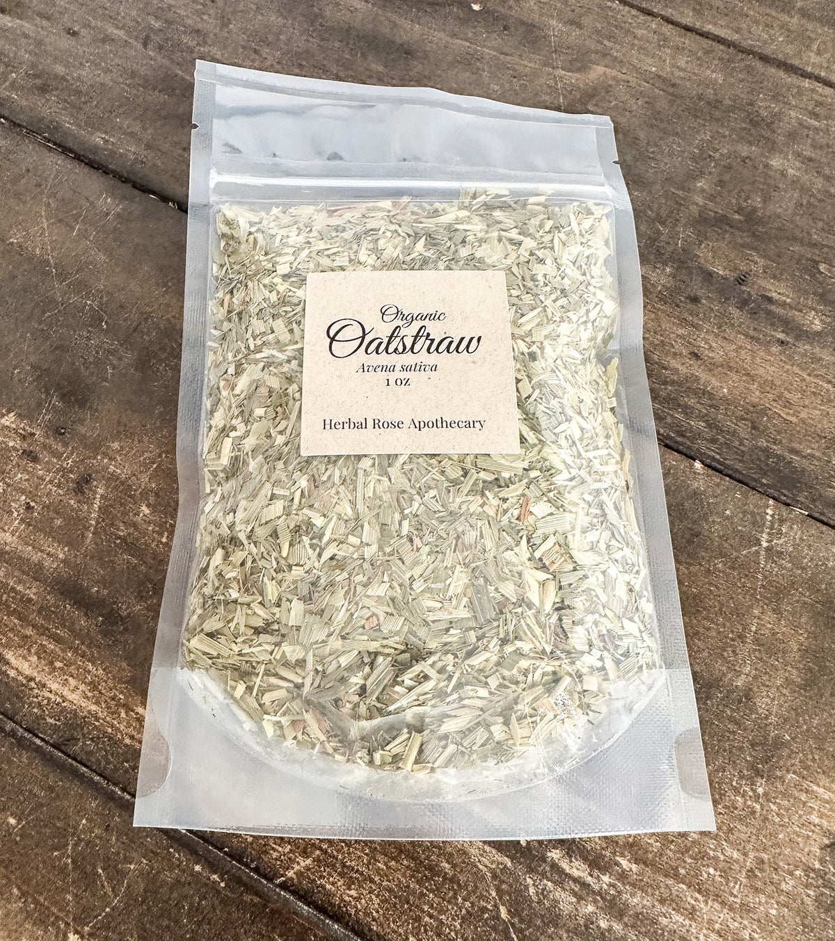 A clear plastic stand-up pouch containing dried organic calibrachae flowers, with a cream paper label reading 'Organic Calibrachae strong nativa 100 Herbal Rose Apothecary,' placed on a rustic dark wood surface.