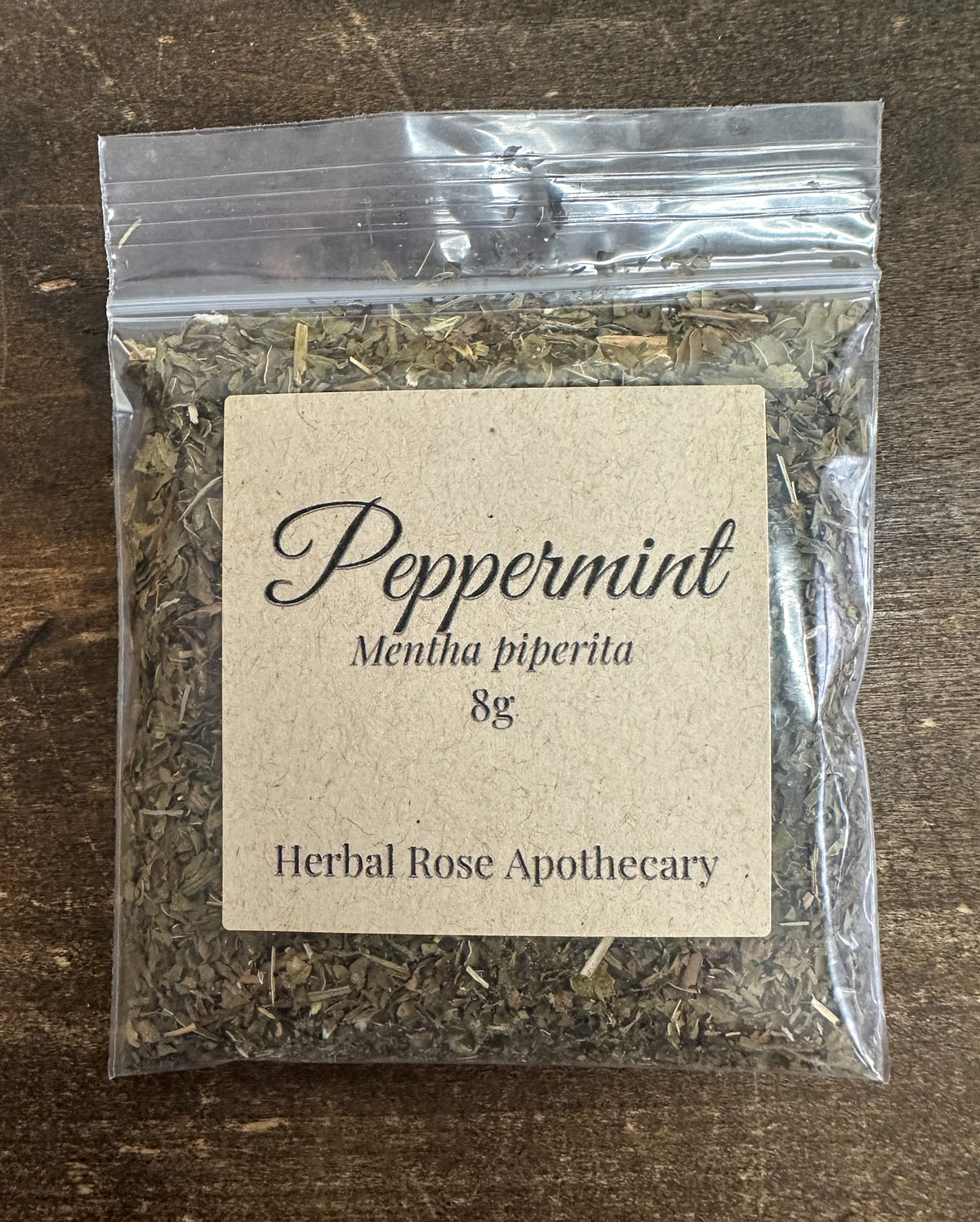 dried peppermint leaves in clear resealable 8g bag  on a wooden surface