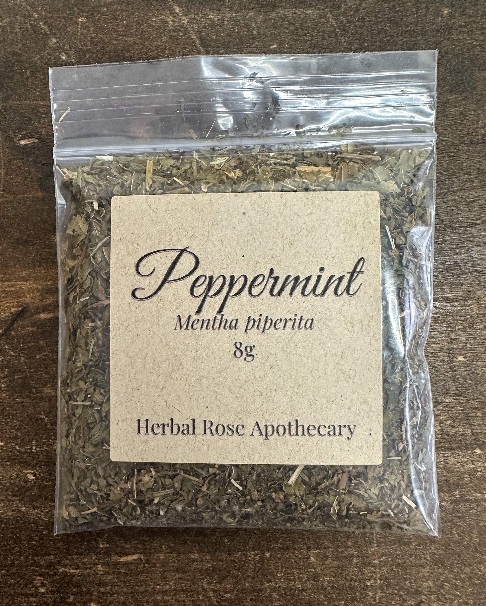 dried peppermint leaves in clear resealable 8g bag  on a wooden surface