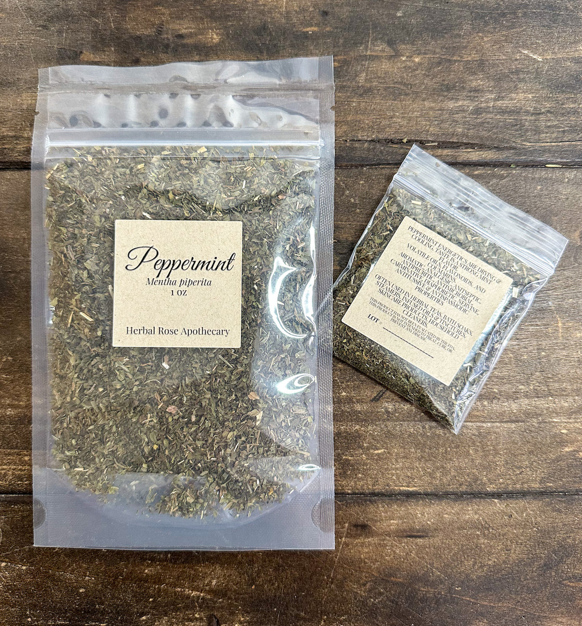 two packages of dried peppermint leaves in clear resealable bags from herbal rose apothecary on a wooden surface