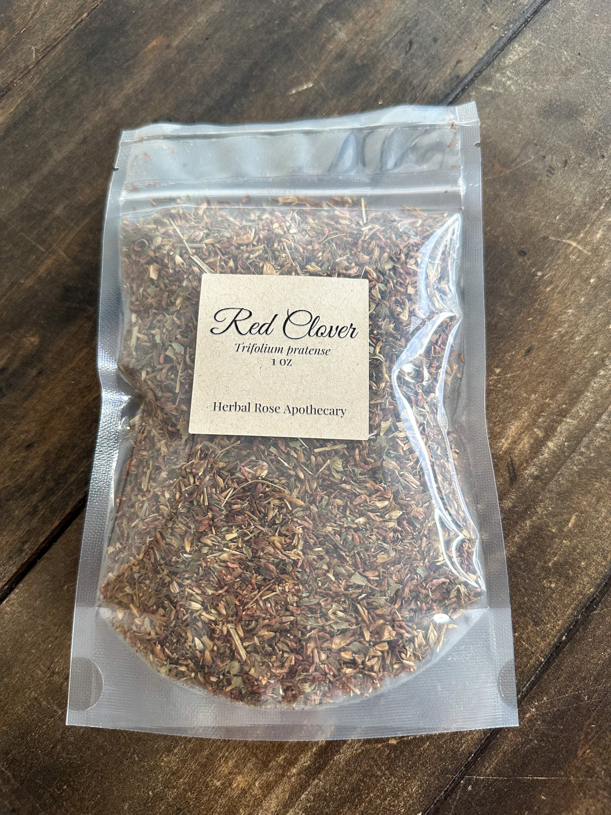 dried red clover leaves in 1oz clear resealable bag on wooden surface