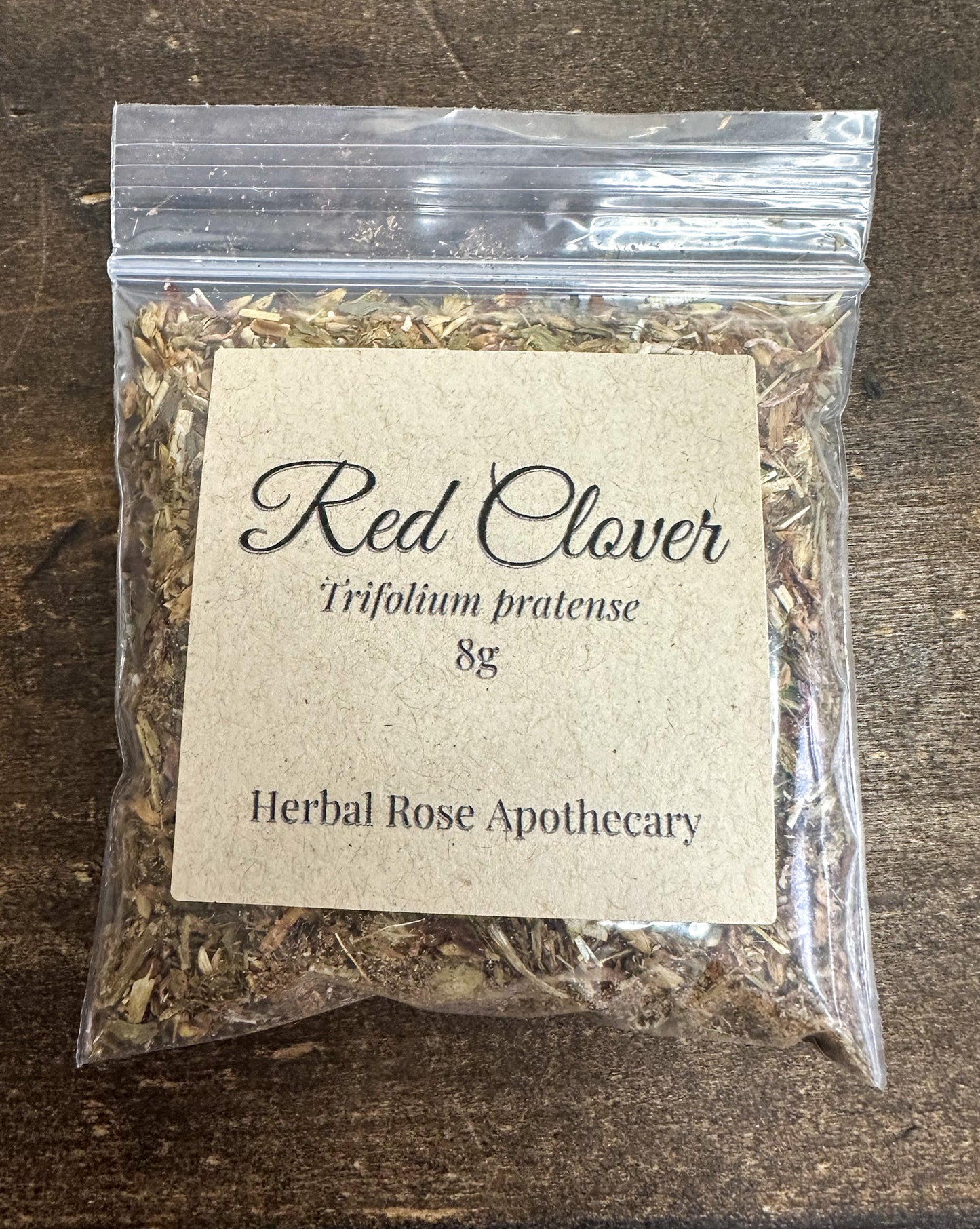dried red clover leaves in 8g clear resealable bag on wooden surface