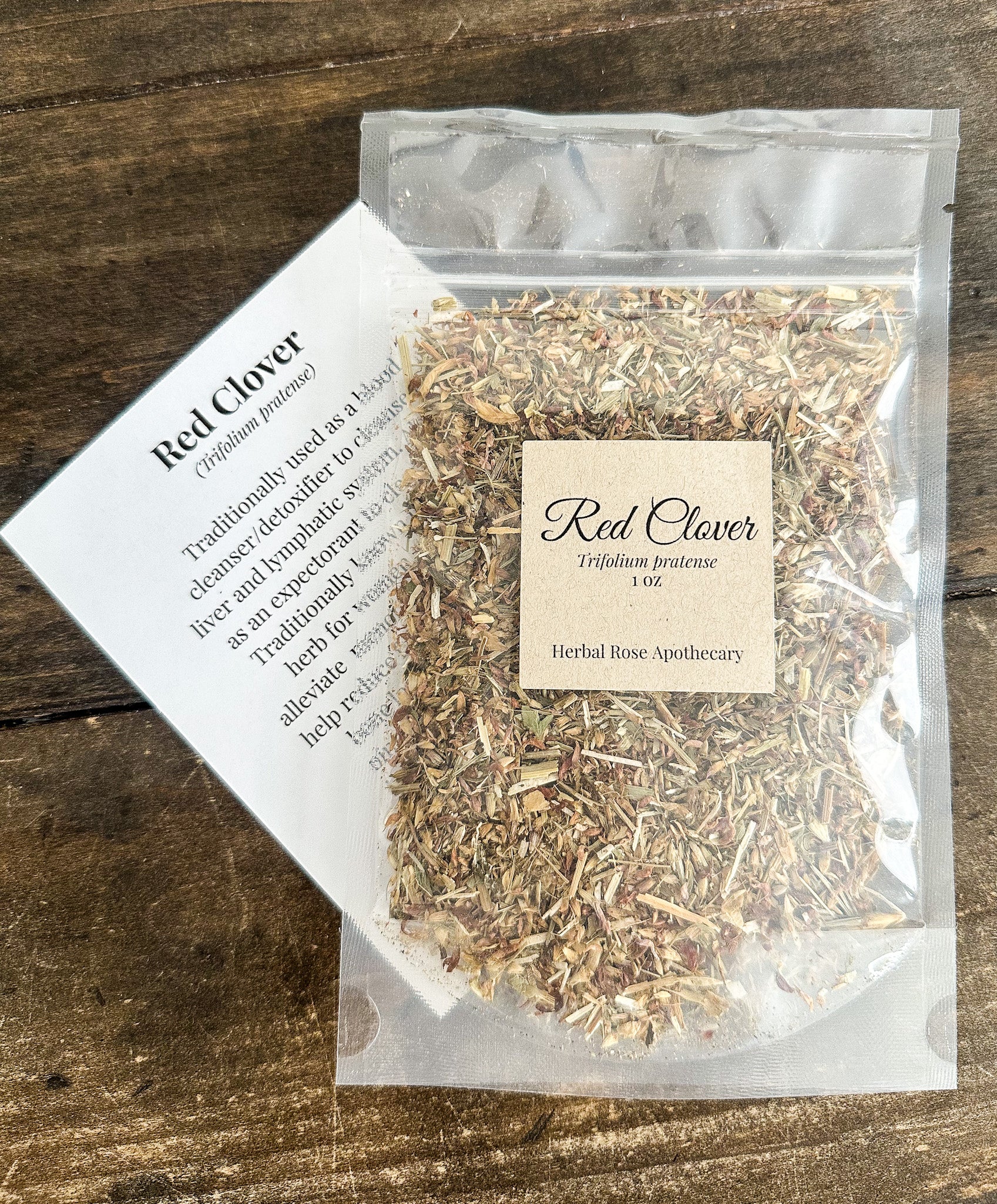 1oz red clover in a clear bag laying on top of a monograph card for red clover with wooden background