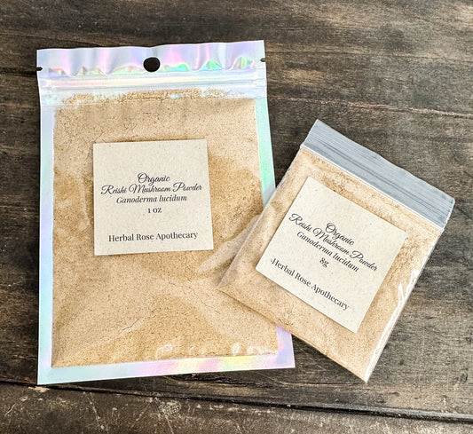 Two packages of Organic Reishi Mushroom Powder from Herbal Rose Apothecary on a wooden surface.