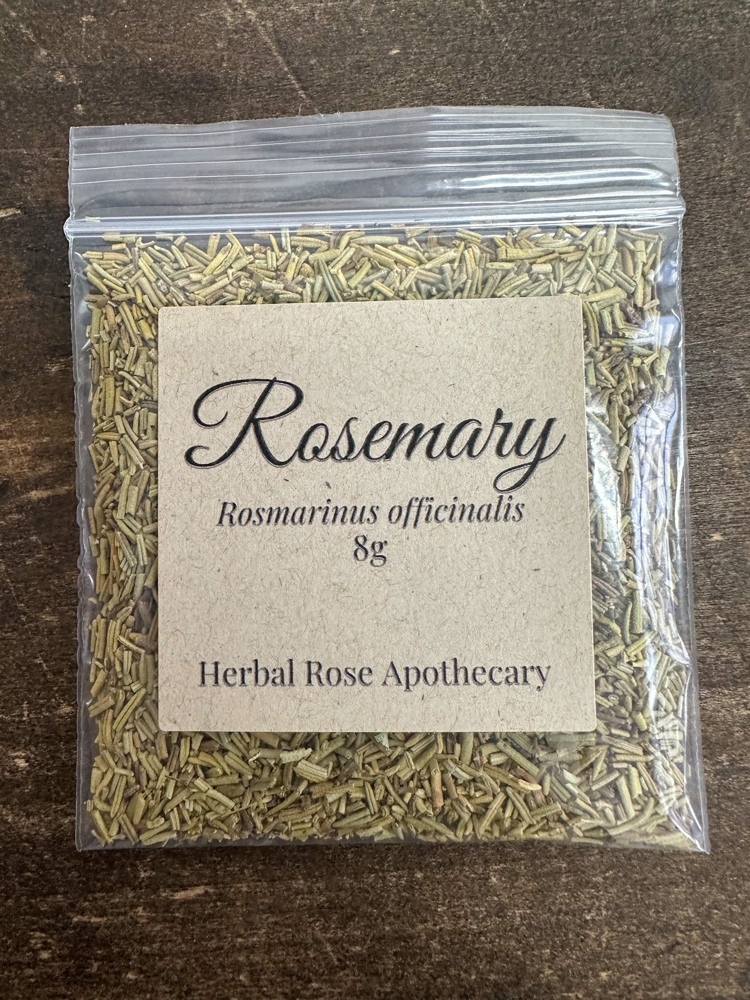 dried rosemary in 8g clear resealable bag on wooden surface