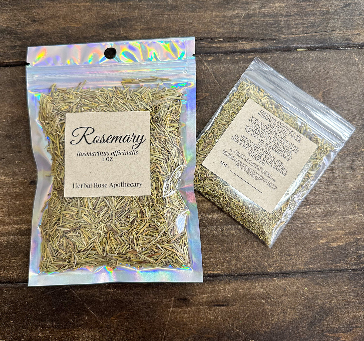 two packages of dried rosemary in clear resealable bags from herbal rose apothecary on a wooden surface