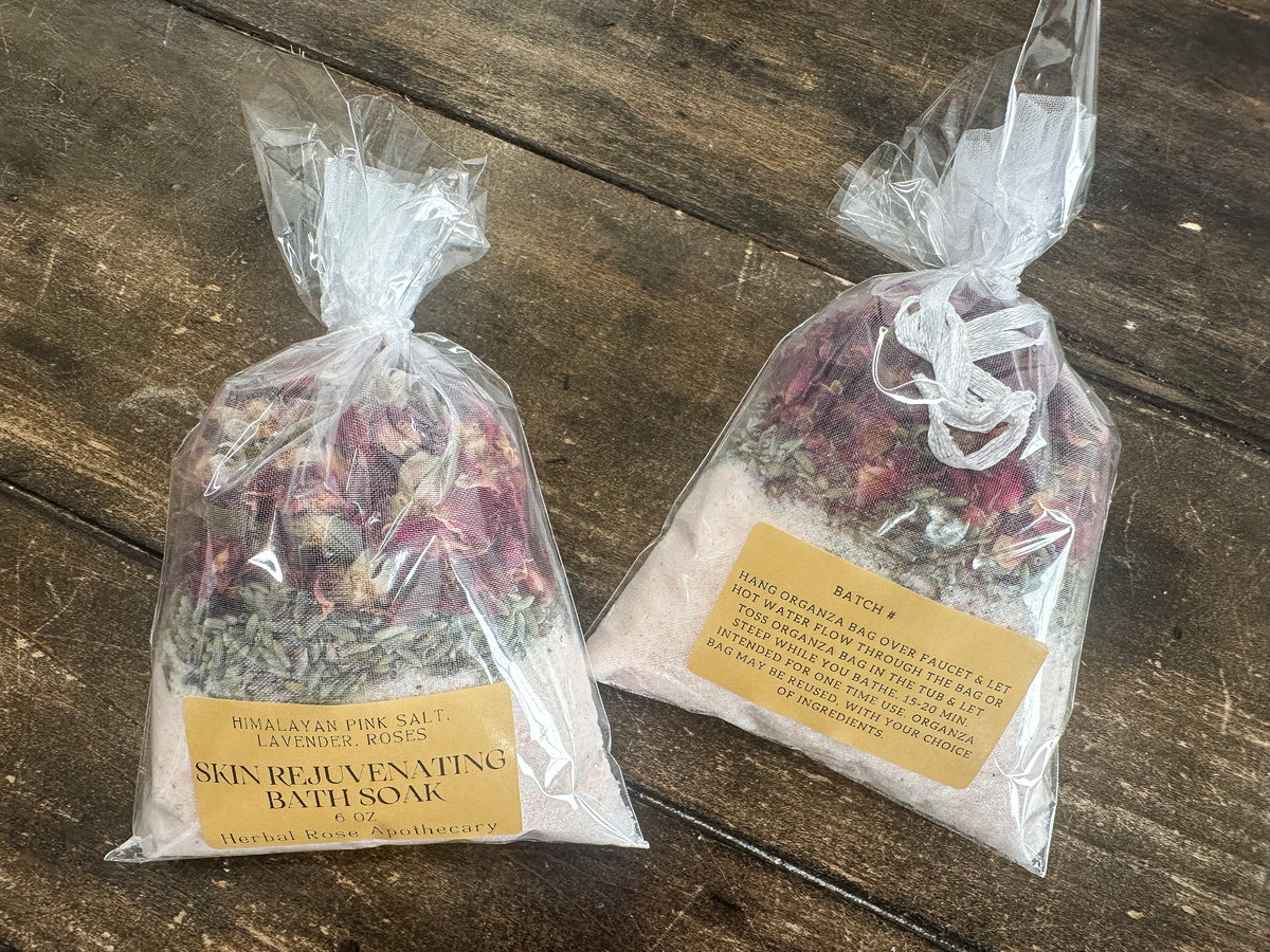 two skin rejuvenating bath soaks packaged in a clear bag and labeled lying on a wooden surface from herbal rose apothecary