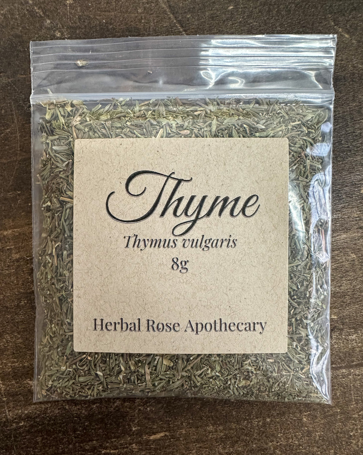 dried thyme leaves in 8g clear resealable bag on wooden surface