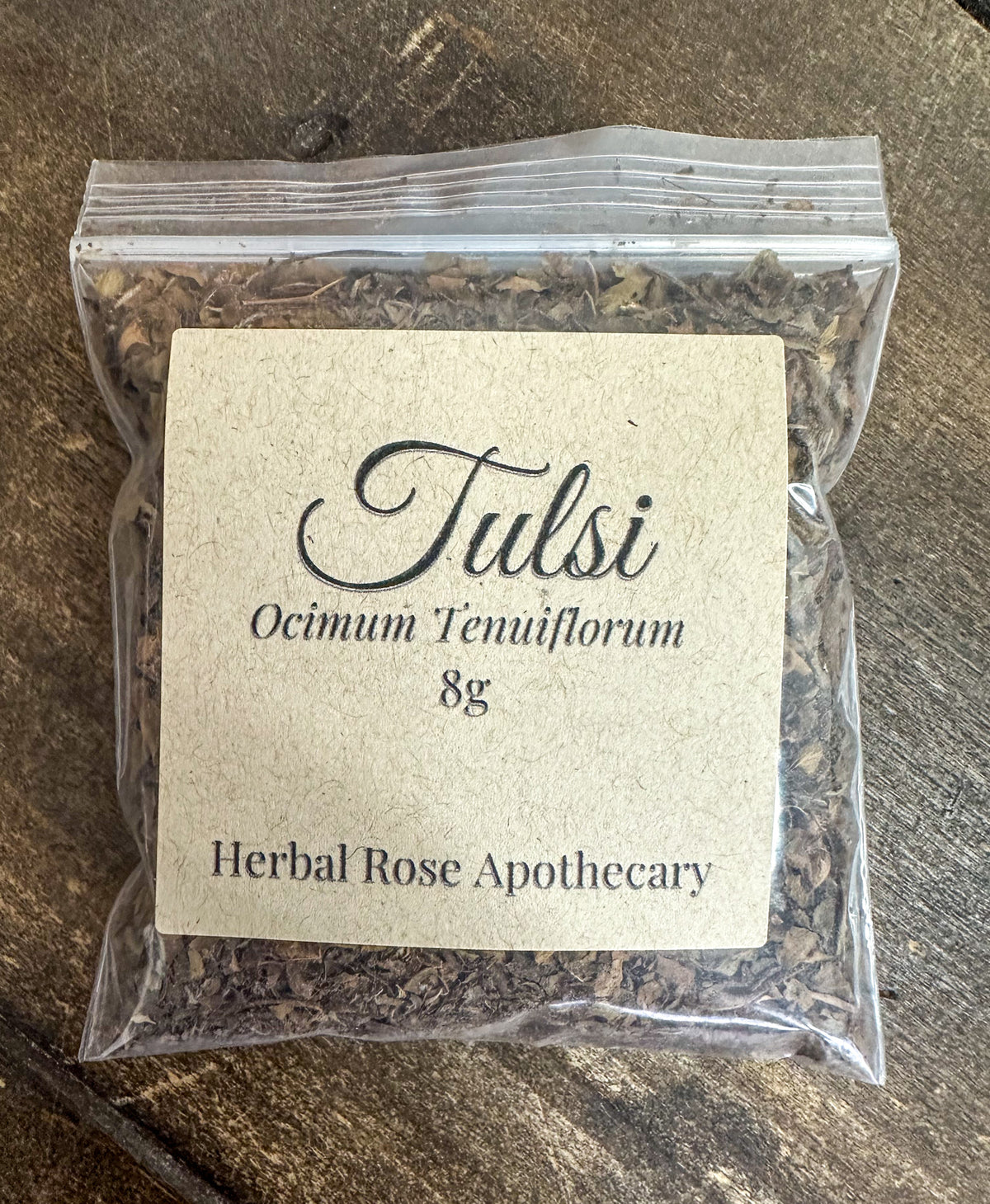 dried tulsi leaves in 8g clear resealable bag on wooden surface