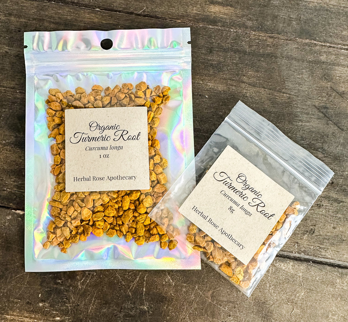 two packages of dried organic turmeric root in clear resealable bags from herbal rose apothecary on a wooden surface